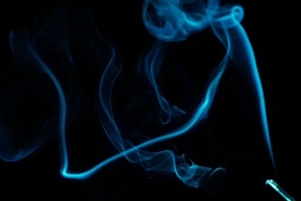 Blunts laid out on a dark surface with smoke trails creating a dynamic effect.