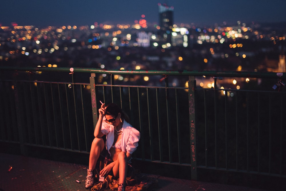 a woman sitting on top of a balcony next to a railing