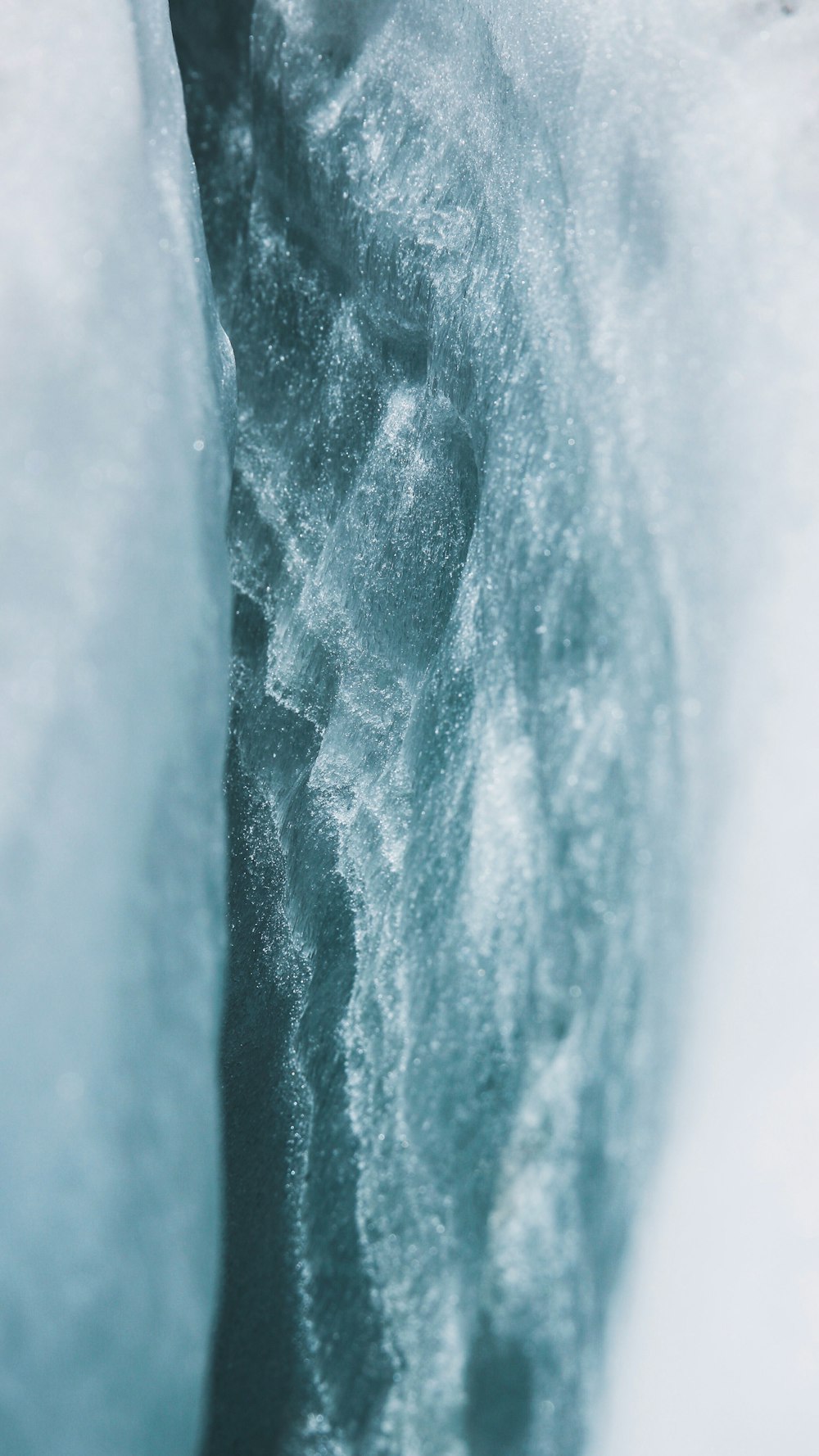 a man is standing in the snow next to a frozen waterfall