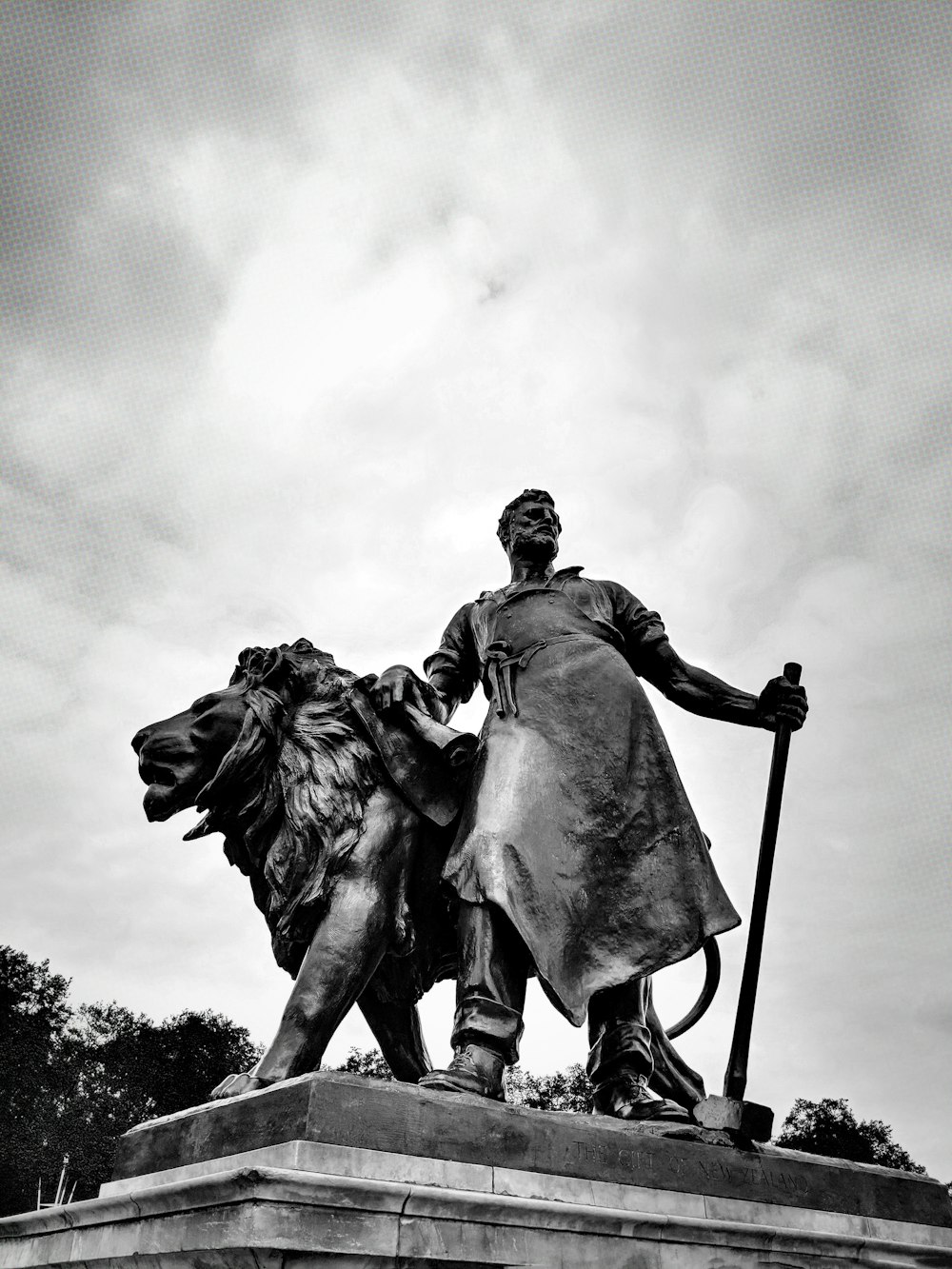 Betonmann neben Löwenstatue