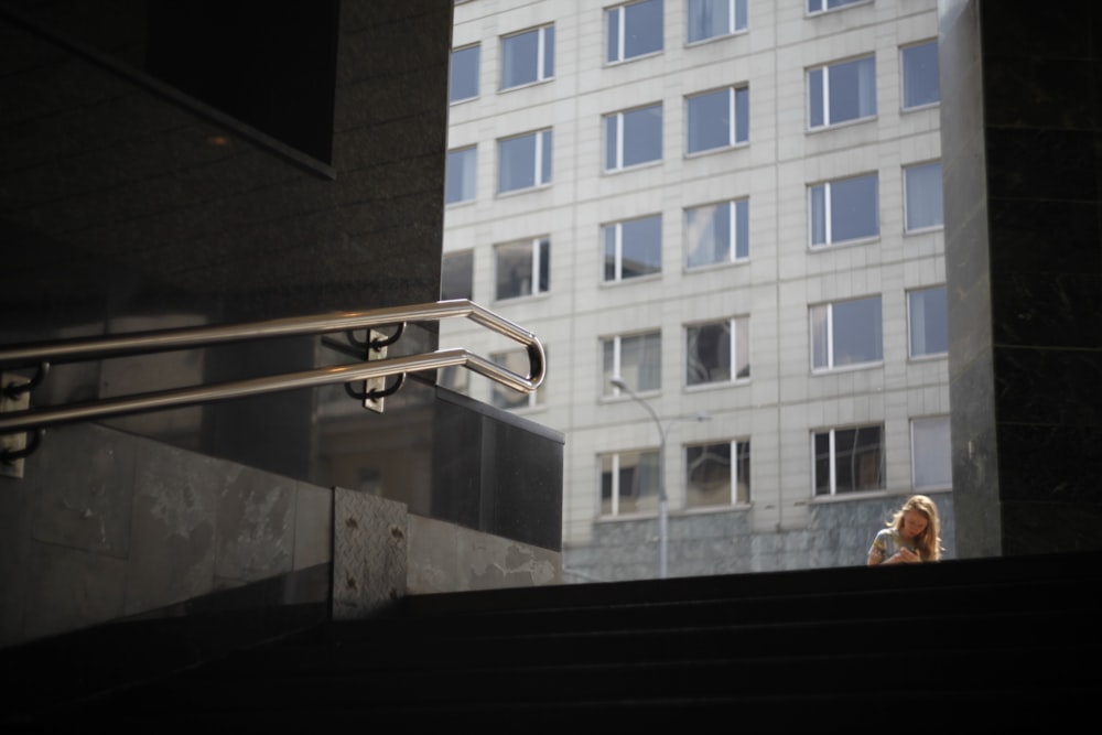 uma mulher descendo um lance de escadas ao lado de um prédio alto