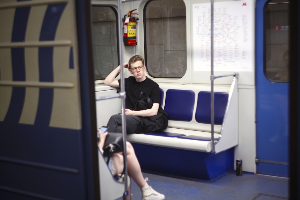 homme assis dans un siège de train bleu et blanc