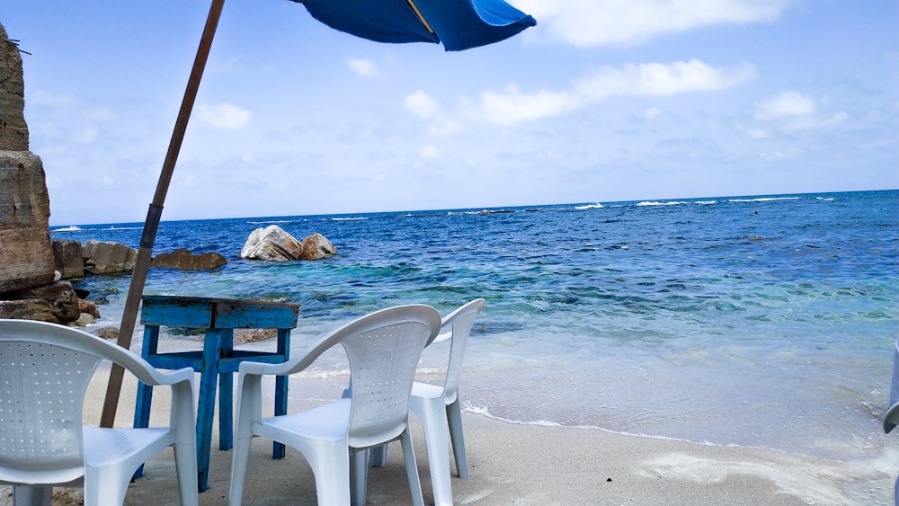 white monobloc armchairs beside sea