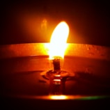 Close-up of a handmade soy wax scented candle with a soft glowing flame.