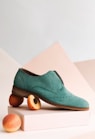 unpaired green leather shoe on top of white box