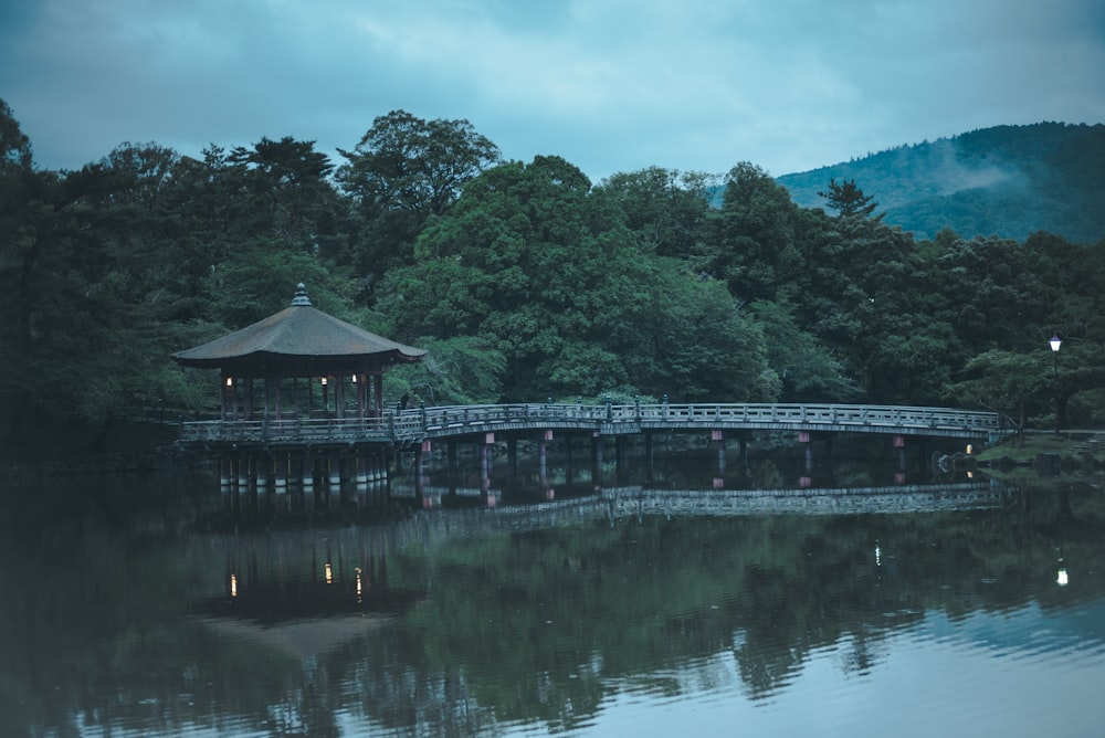 a gazebo sitting on top of a lake next to a forest