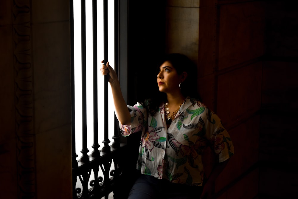 woman wearing whtie and green floral top holding on black steel bar