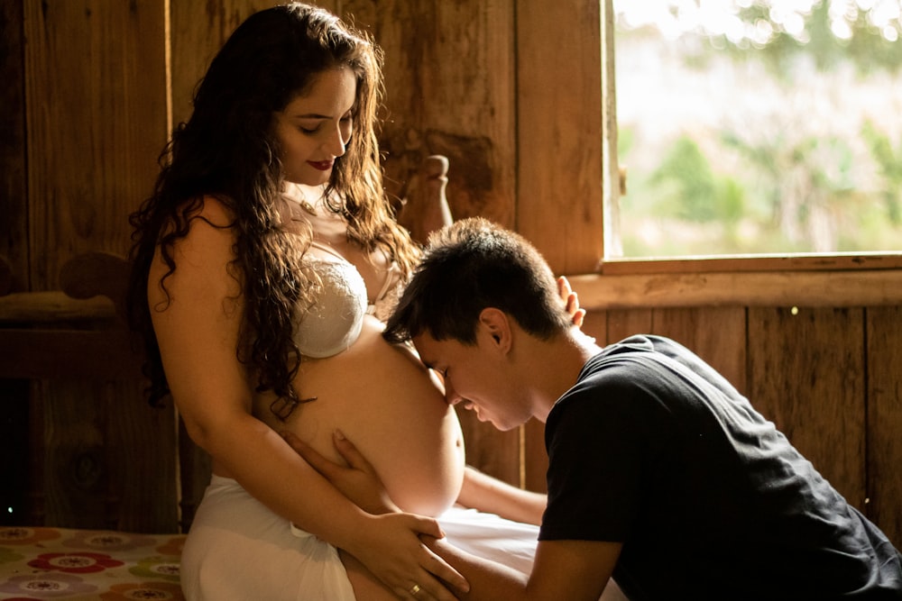 man kneeling on pregnant woman