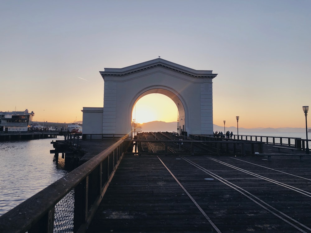 white concrete arch near body of water