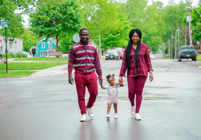 Family walking along a paved street in a sunny new neighborhood.