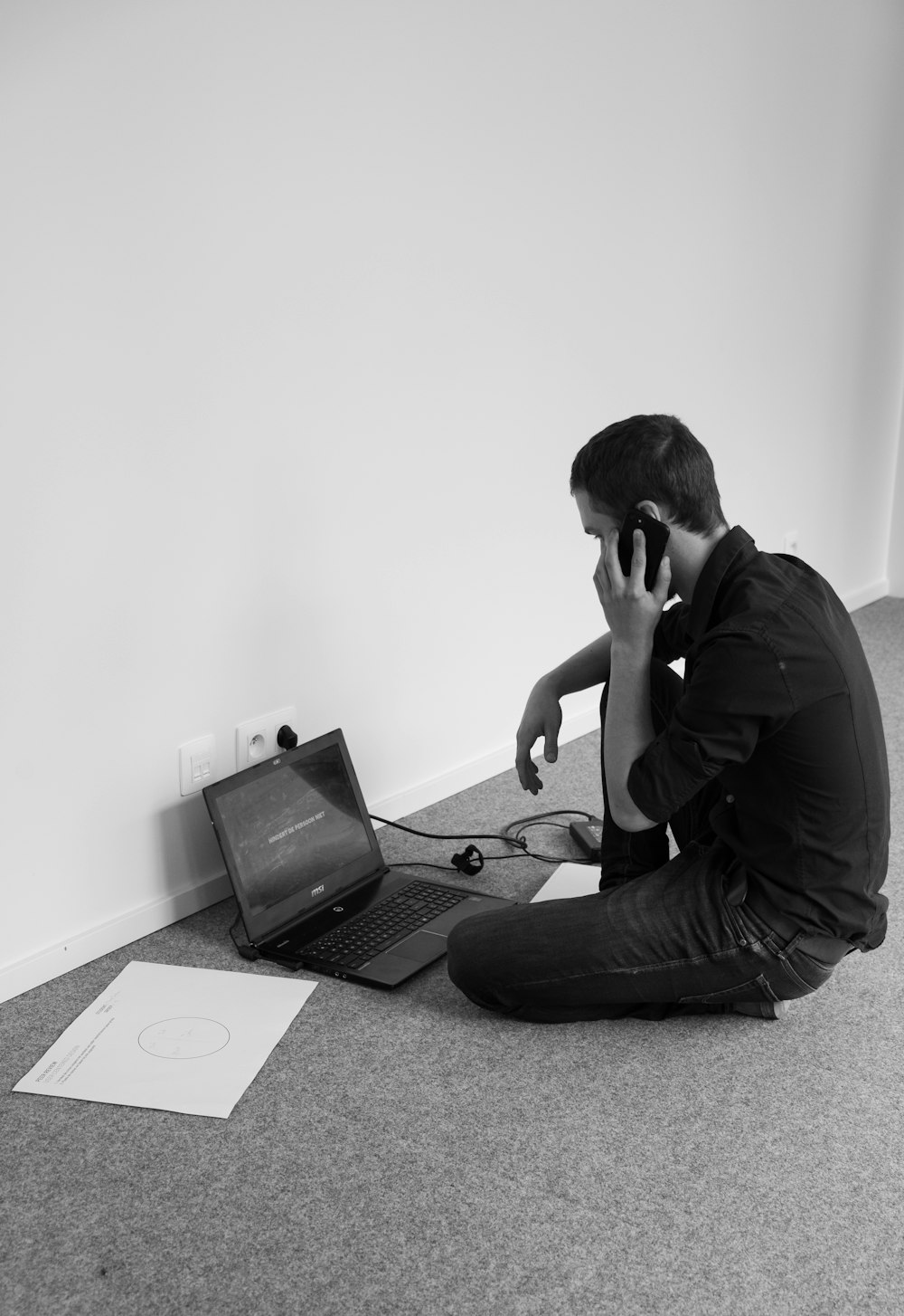 grayscale photography of of man sitting beside laptop computer