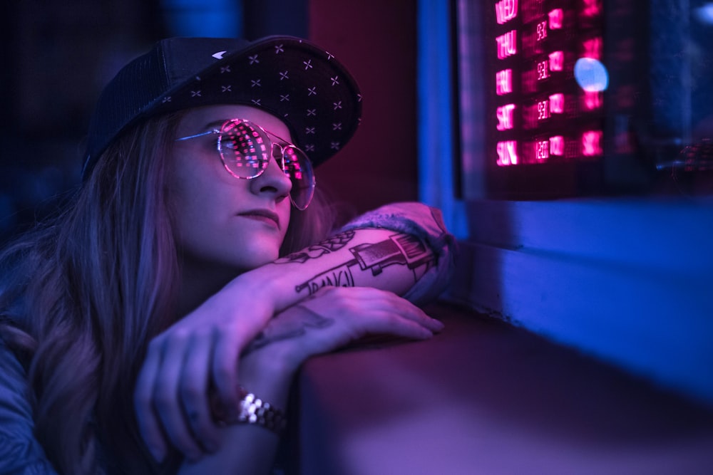 woman wearing black cap looking at purple LED light