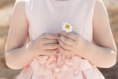 Close-up of a little girl’s hands holding a tiny flower accessory from Infantiles Diablitos.