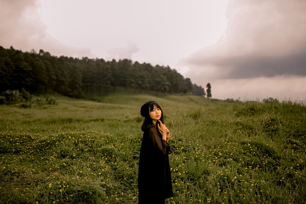 girl in black dress standing in green grass field