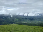 a lush green hillside covered in clouds and grass