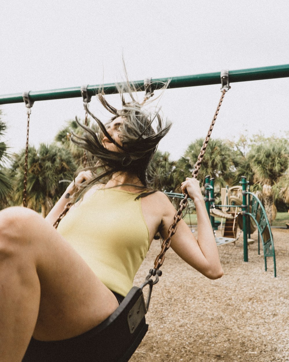 woman wearing yellow top on swing