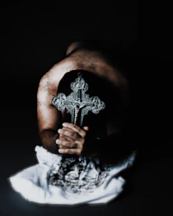 Close-up of a person praying peacefully with a glowing cross in the background