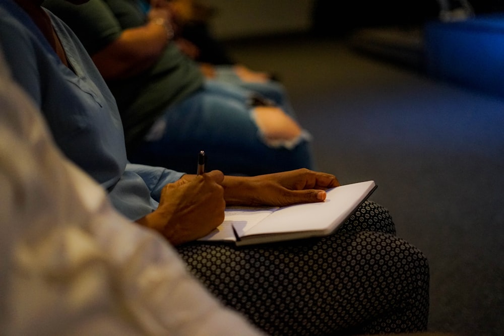 personne tenant un stylo et du papier blanc sur les genoux de la personne