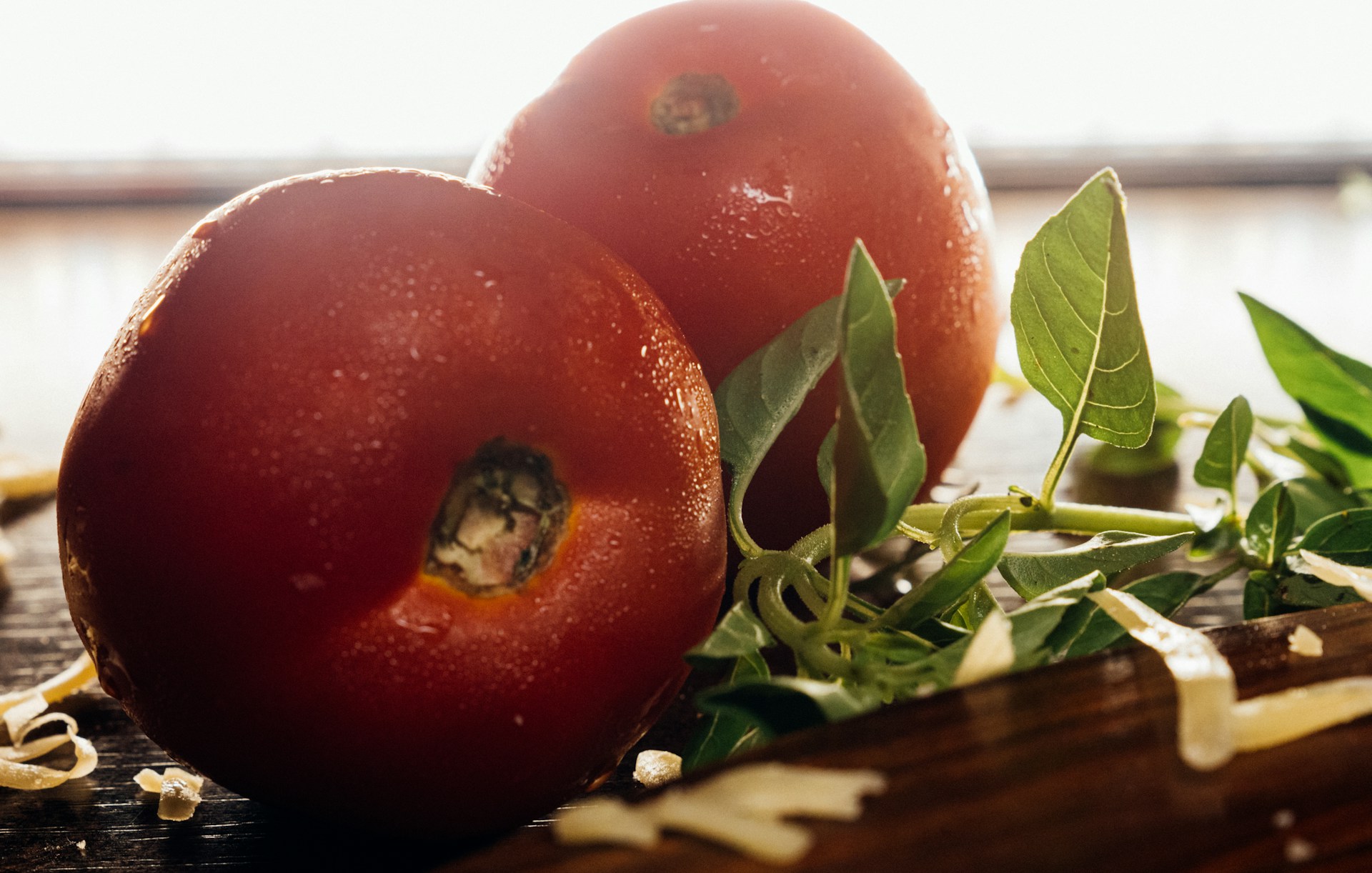 Fresh ingredients laid out on a rustic wooden counter: ripe tomatoes, fresh mozzarella, basil, and olive oil.