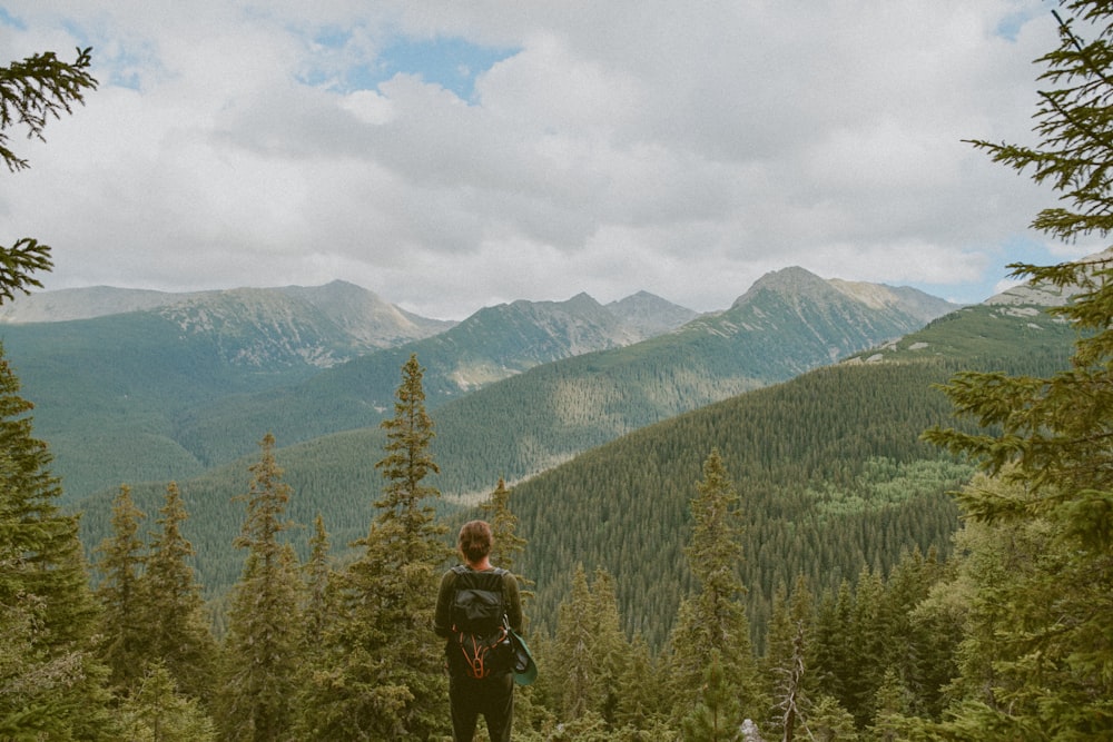 woman standing in front of pine trees during daytime