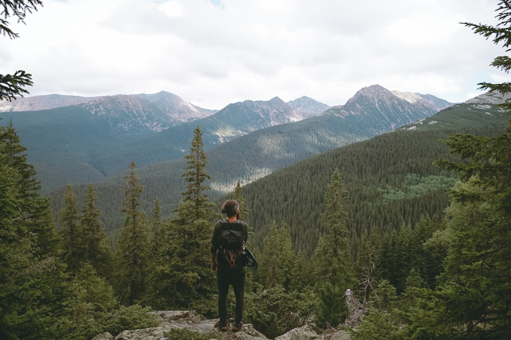 person standing beside green mountain during daytime