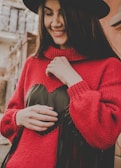A model wearing a bright red brushed knit hat, smiling against a city street backdrop.