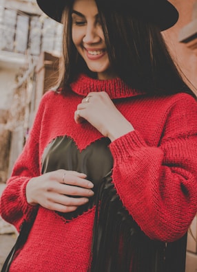 A model wearing a bright red brushed knit hat, smiling against a city street backdrop.