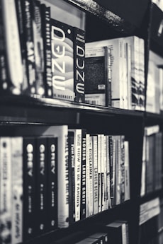 grayscale photography of books in bookcase