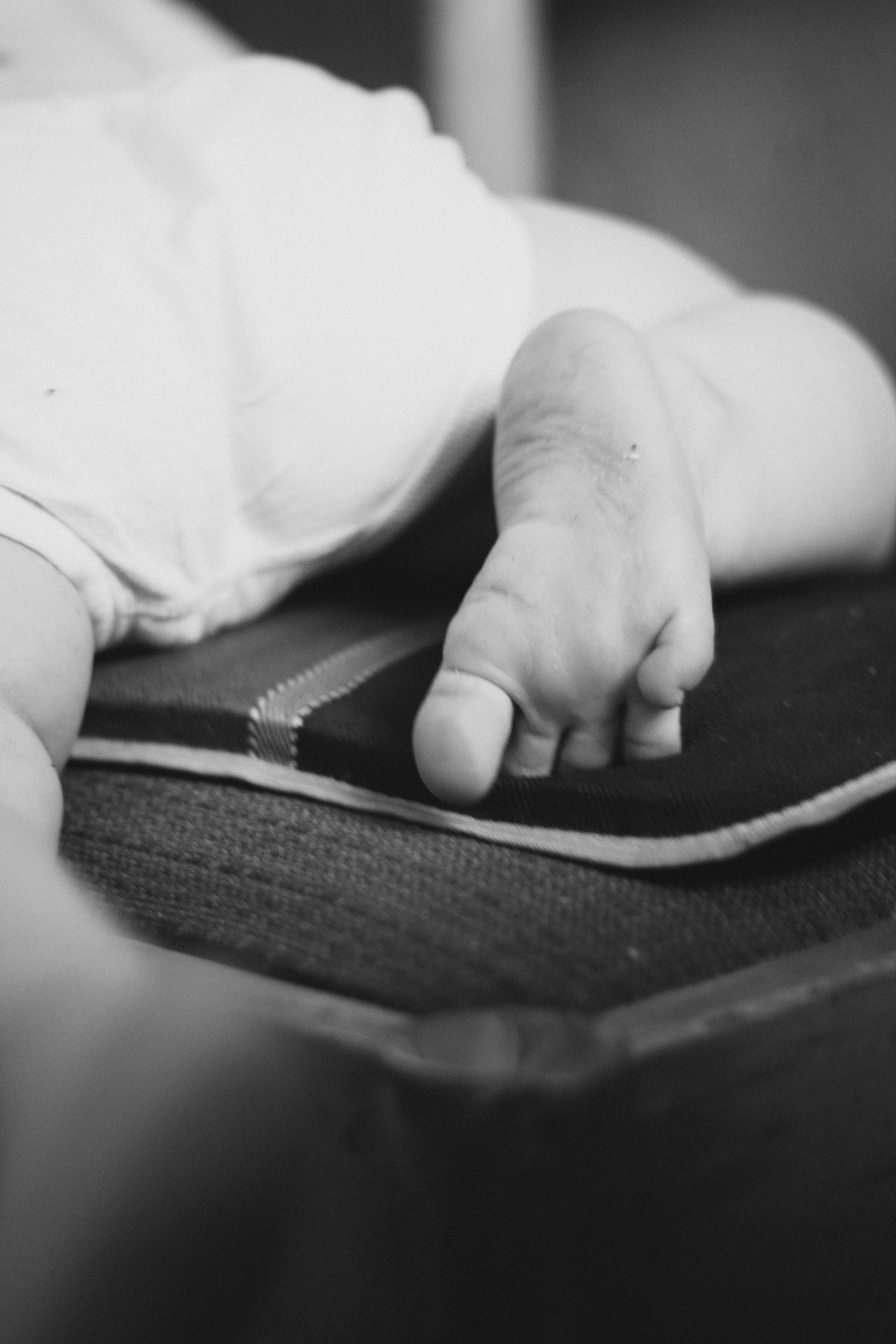 a black and white photo of a baby's hand on a book