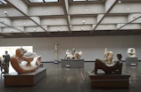 Visitors exploring a virtual gallery room filled with sculptures and mixed media art.