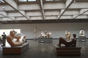 Visitors exploring a virtual gallery room filled with sculptures and mixed media art.
