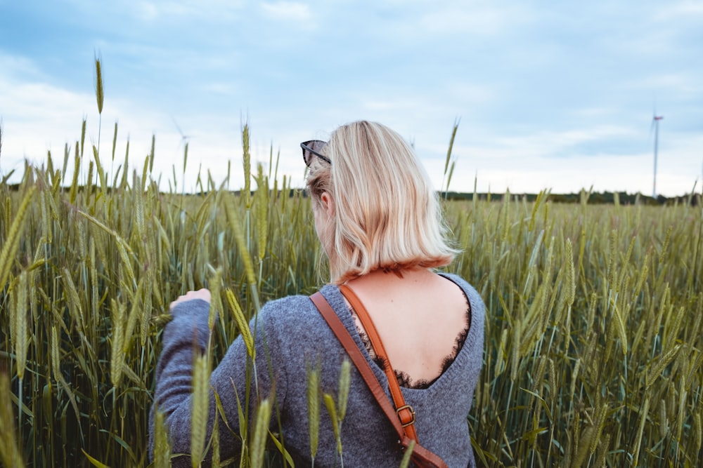 woman wearing gray long-sleeved shirt walking on grass field during daytime