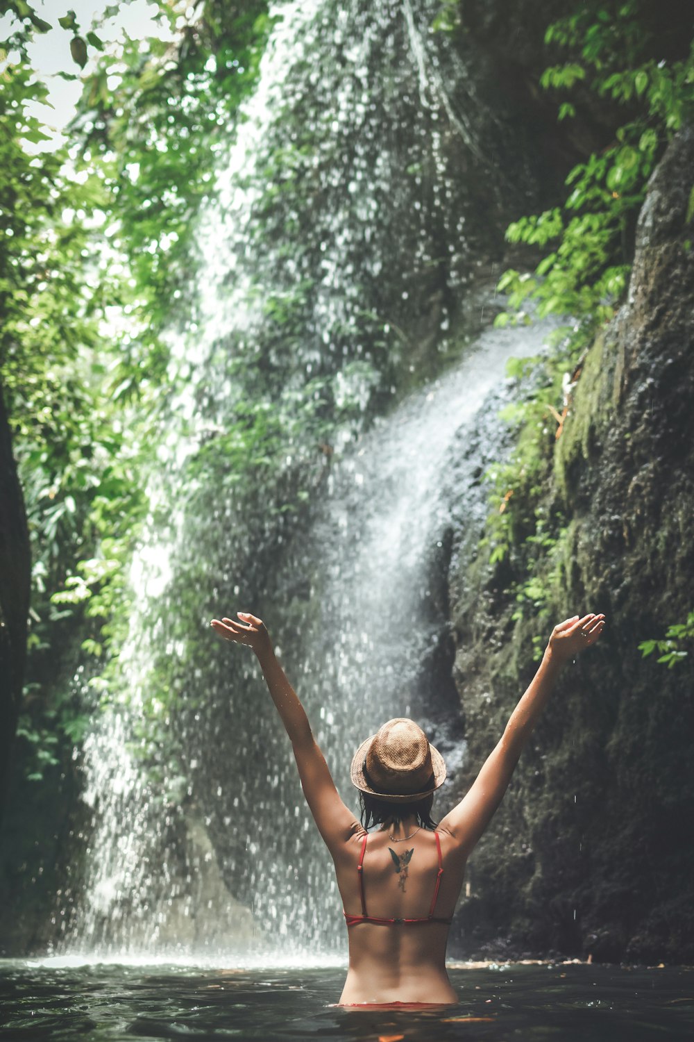 woman wearing red bikini top across waterfalls