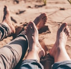 close-up photography of human feet on brown sand during daytime