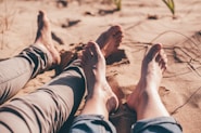 close-up photography of human feet on brown sand during daytime