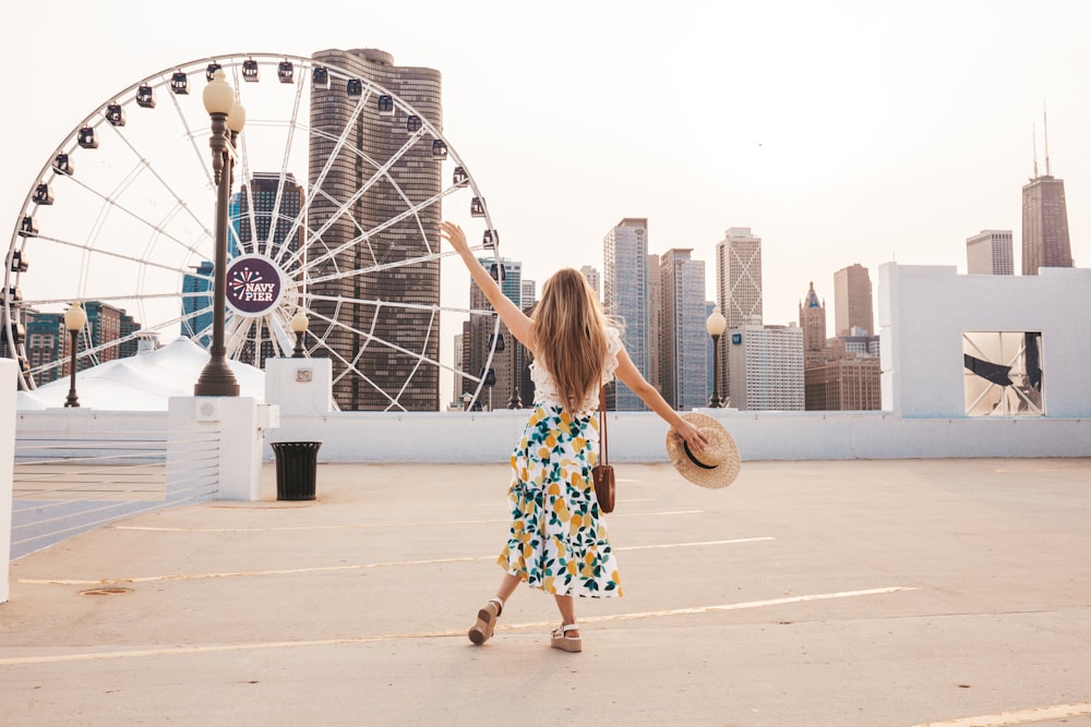 woman in white and blue floral dress holding hat