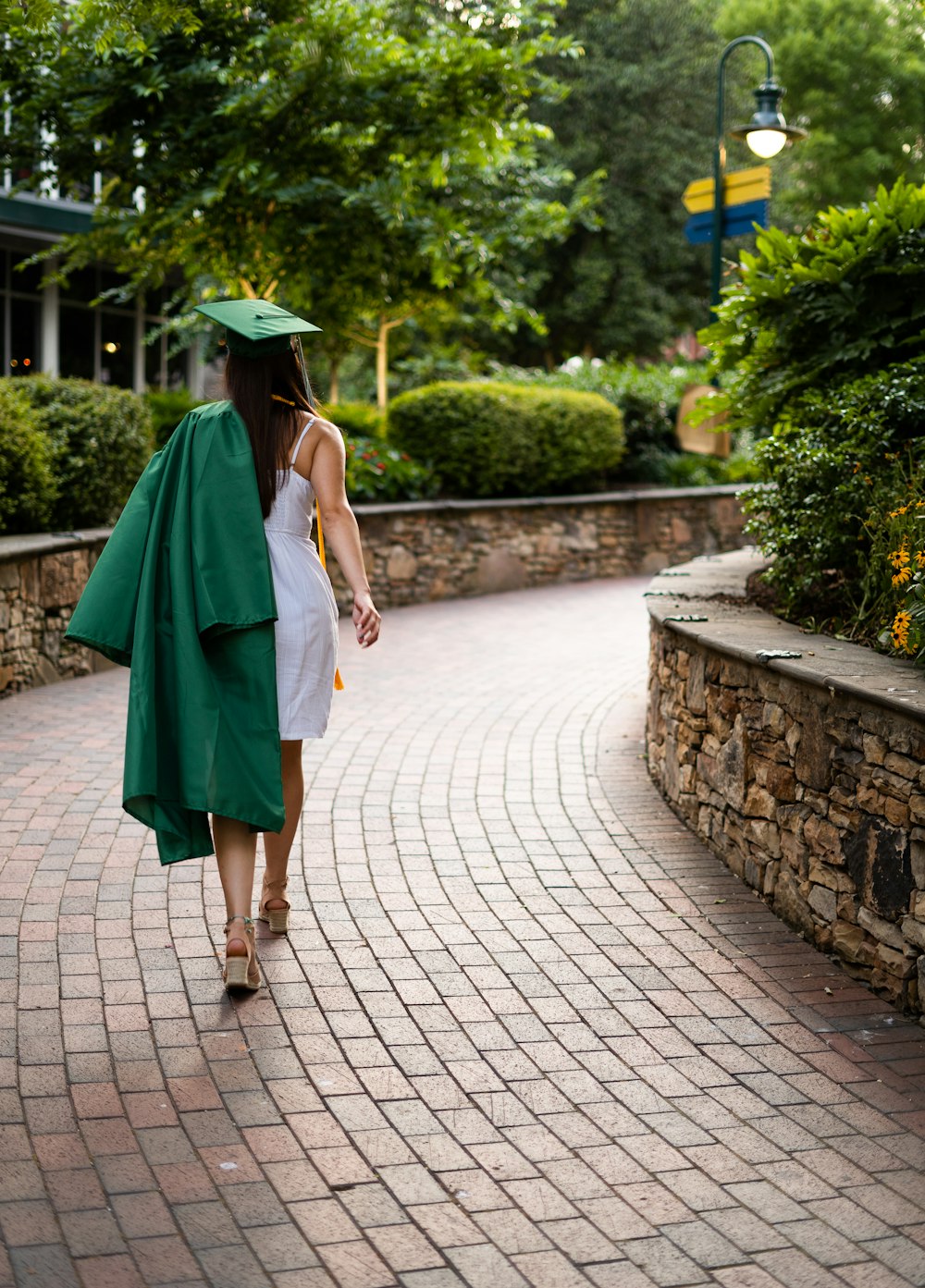 Persona desconocida con vestido académico caminando al aire libre