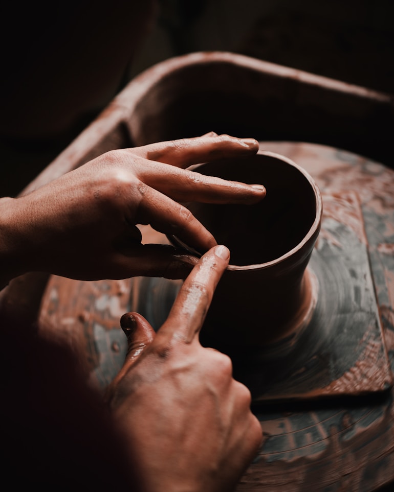 person crafting clay pot