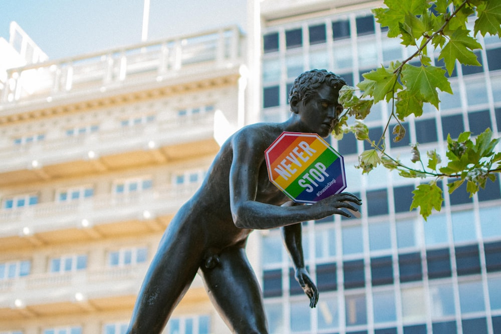 black naked statue holding Never Stop-printed multicolored sign