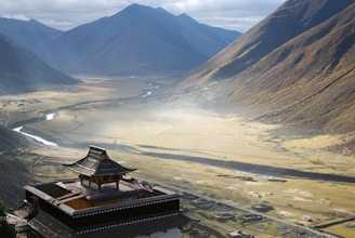 red and brown wooden house near green field viewing mountain under blue and gray skies