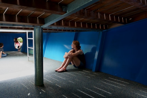 A thoughtful teenager sitting alone in a school corridor, looking reflective.