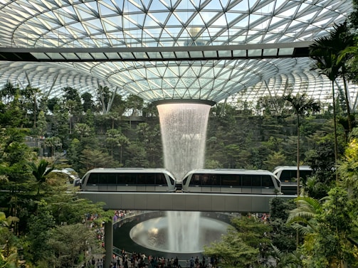 train near trees inside building with indoor waterfalls