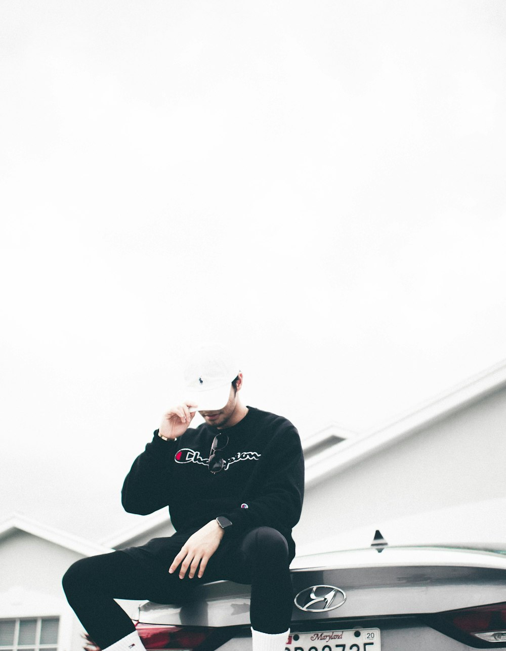 man in black Champion crew-neck long-sleeved shirt sitting on car