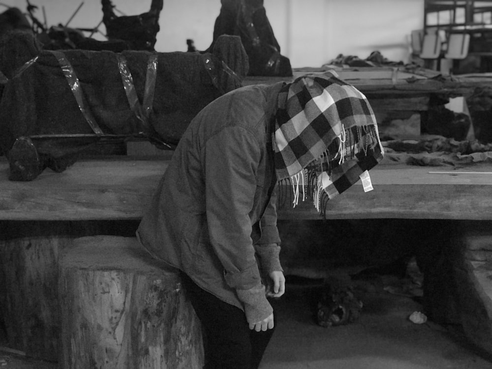 grayscale photo of person sitting on log