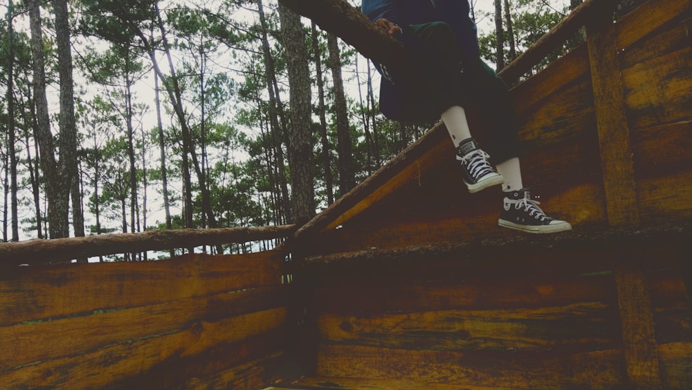 person wearing black and white sneakers on brown wooden surface