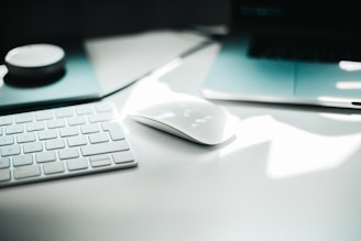 A modern workspace with a laptop, keyboard, and tech accessories on a clean desk.