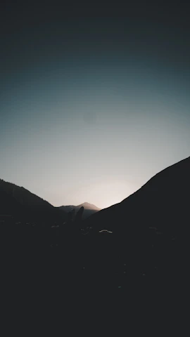 A serene view of Kodaikanal hills under a partly cloudy sky at dawn.