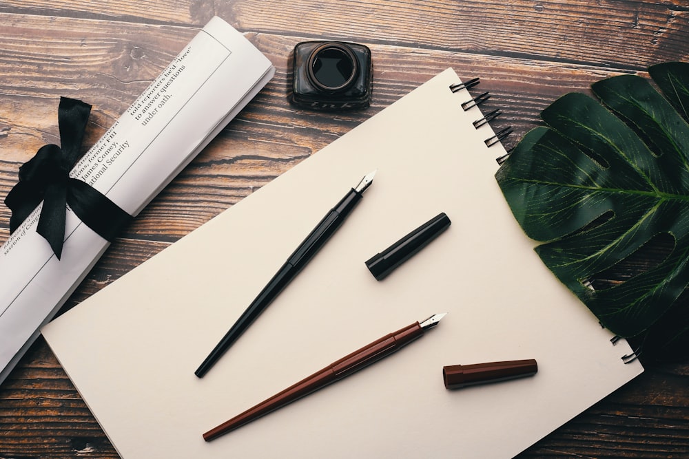 two red and black fountain pens on top of white printer paper