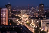 A dynamic cityscape at dusk, showcasing illuminated buildings and bustling streets.