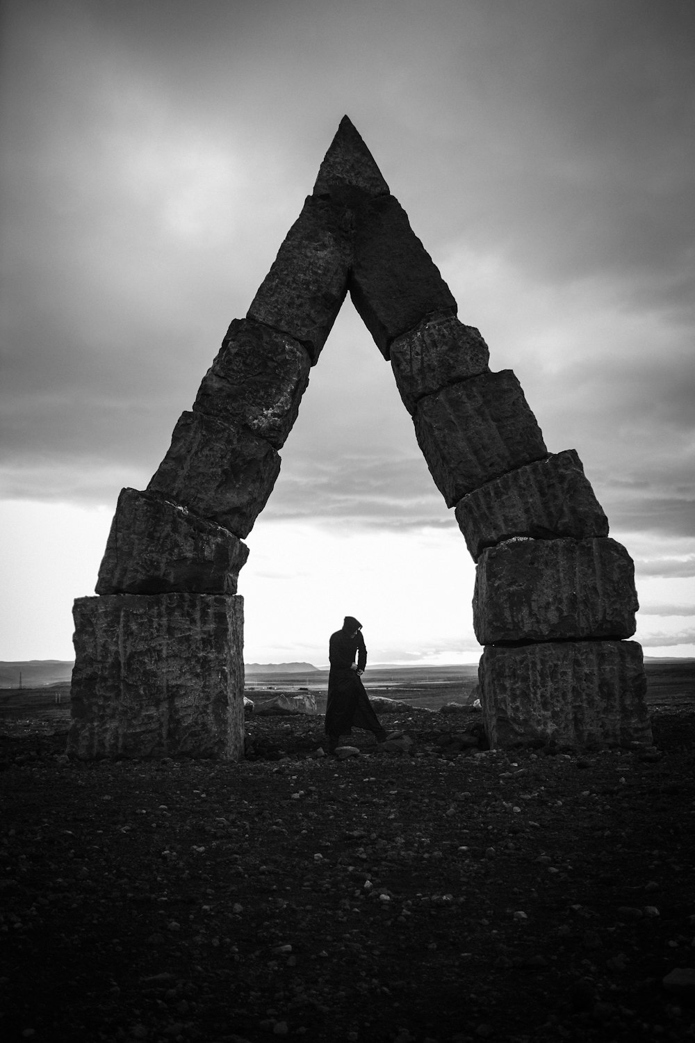 grayscale photography of person standing near arch decor